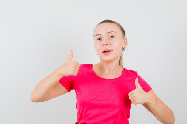 Mulher jovem mostrando dois polegares para cima em uma camiseta e parecendo alegre