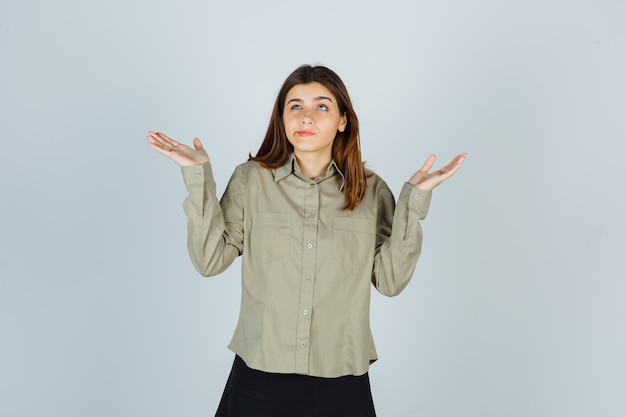 Mulher jovem mostrando gesto de impotência enquanto curva os lábios na camisa