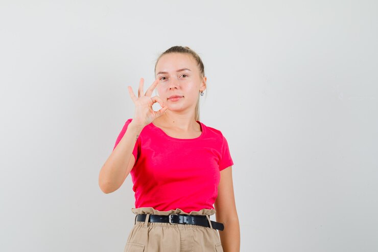 Foto grátis mulher jovem mostrando gesto de ok com camiseta e calça parecendo confiante