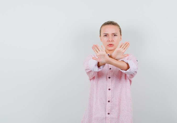 Foto grátis mulher jovem mostrando gesto de parada com uma camisa rosa e parecendo séria