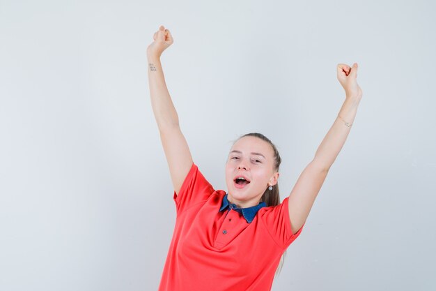 Mulher jovem mostrando gesto de vencedor com uma camiseta e parecendo feliz