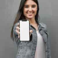 Foto grátis mulher jovem, mostrando, smartphone, em, mão