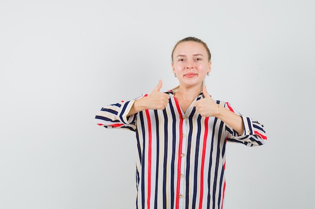 Foto grátis mulher jovem mostrando um gesto semelhante com as duas mãos na blusa listrada e parecendo feliz