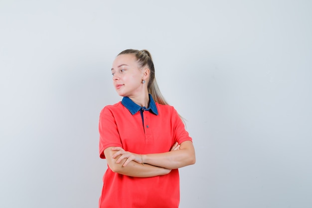 Mulher jovem olhando para trás com os braços cruzados em uma camiseta e parecendo confiante