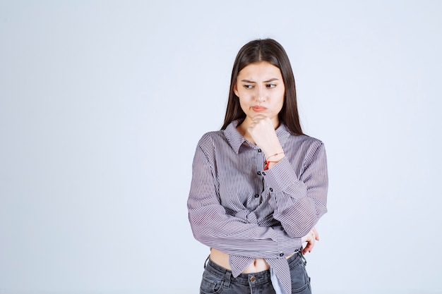 Mulher jovem parece pensativa e com brainstorming