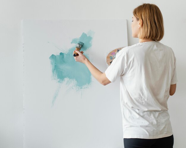 Mulher jovem pintando com acrílico sobre tela