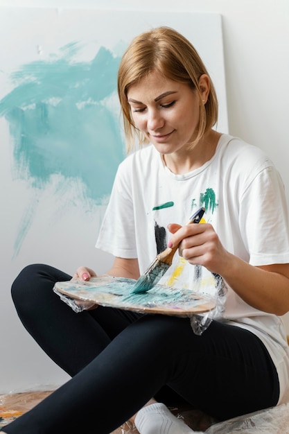 Foto grátis mulher jovem pintando com acrílico sobre tela