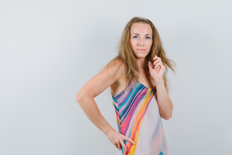 Foto grátis mulher jovem posando em pé com um vestido de verão e parecendo glamorosa