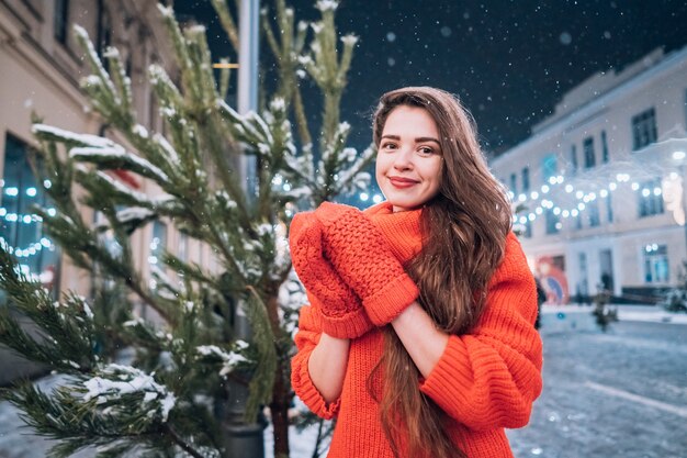 Mulher jovem posando perto da árvore de Natal na rua