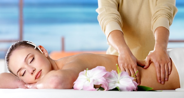 Foto grátis mulher jovem relaxando em um salão de spa e recebendo massagem corporal