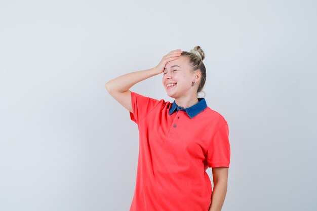 Mulher jovem rindo enquanto segura a mão na testa em uma camiseta