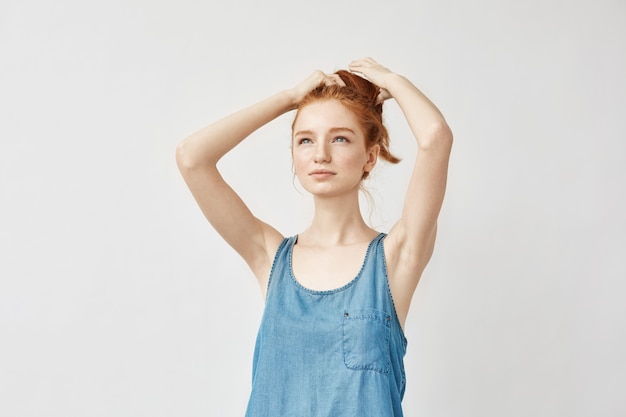 Mulher jovem ruiva corrigindo o corte de cabelo.