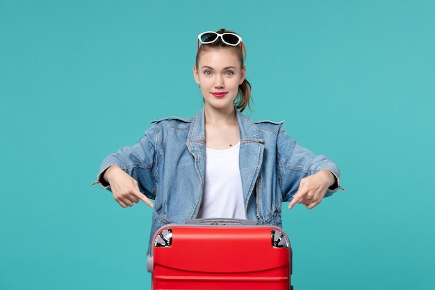 Mulher jovem se preparando para a viagem com sua bolsa vermelha na mesa azul