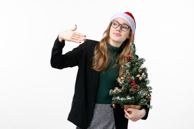 Mulher jovem segurando a árvore de Natal na mesa branca, brinquedo de Natal de ano novo