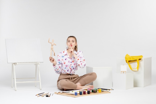 Mulher jovem segurando a figura humana de brinquedo de frente para o fundo branco