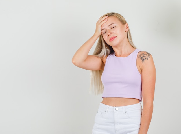 Mulher jovem segurando a mão na testa com os olhos fechados em camiseta