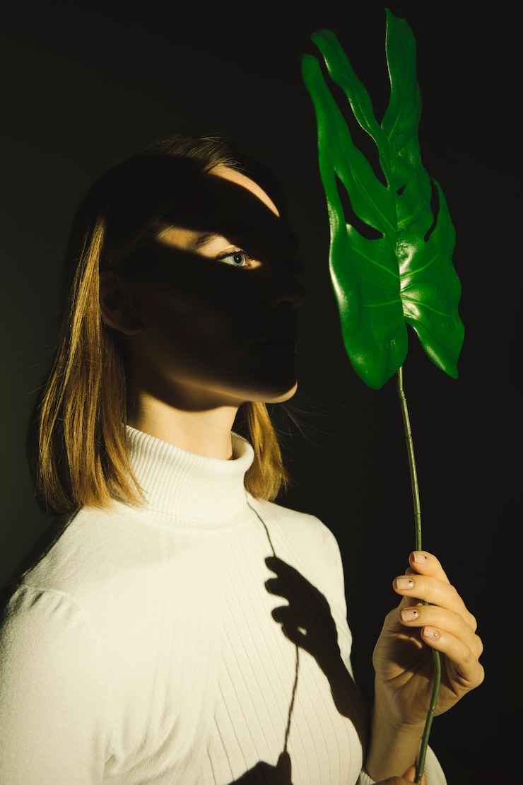 Foto grátis mulher jovem, segurando, folha verde, em, rosto