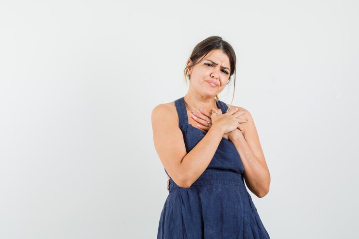 Foto grátis mulher jovem segurando o peito com as mãos no vestido e parecendo dolorida
