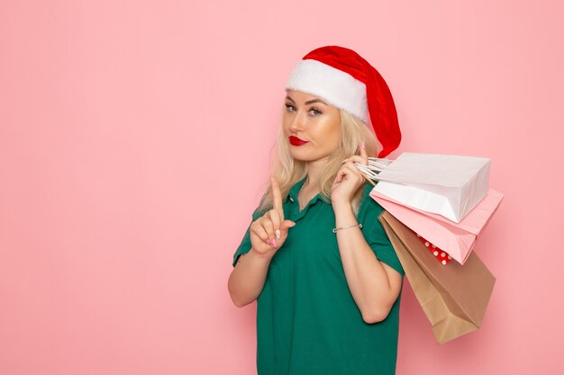 Mulher jovem segurando os presentes de Natal em pacotes na parede rosa modelo de férias de Natal de ano novo.