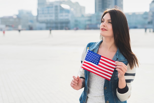 Foto grátis mulher jovem, segurando, pequeno, bandeira americana, durante, celebração, de, dia independência