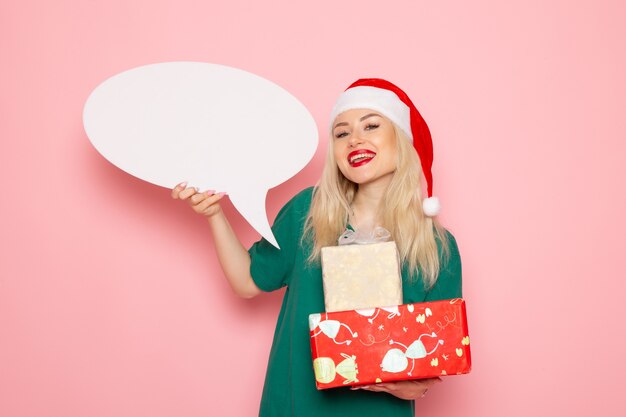 Mulher jovem segurando presentes de natal e placa branca na parede rosa emoção mulher presente neve foto a cores feriado de ano novo