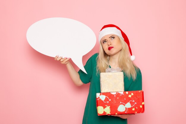 Mulher jovem segurando presentes de natal e placa branca na parede rosa mulher presente cor de neve feriado de ano novo