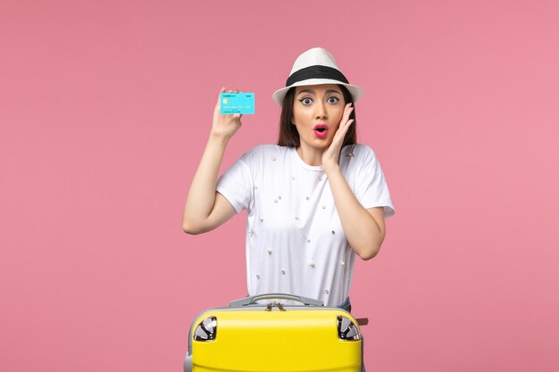Mulher jovem segurando um cartão de banco azul na parede rosa mulher de frente