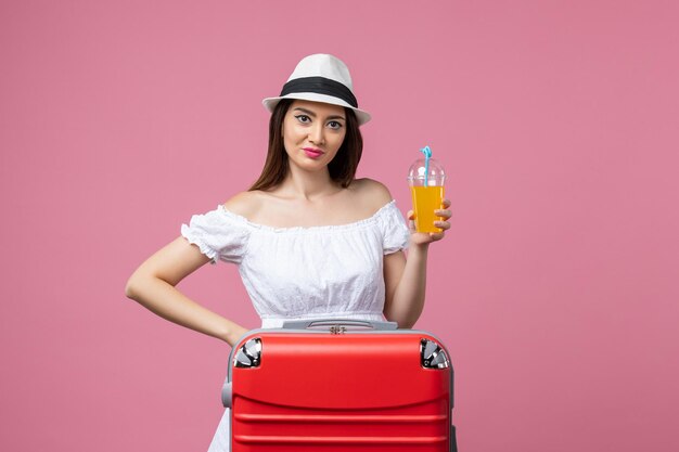 Mulher jovem segurando um coquetel nas férias de verão na parede rosa.