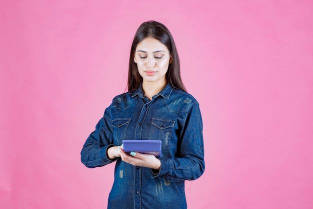 Mulher jovem segurando uma calculadora azul na mão e calculando