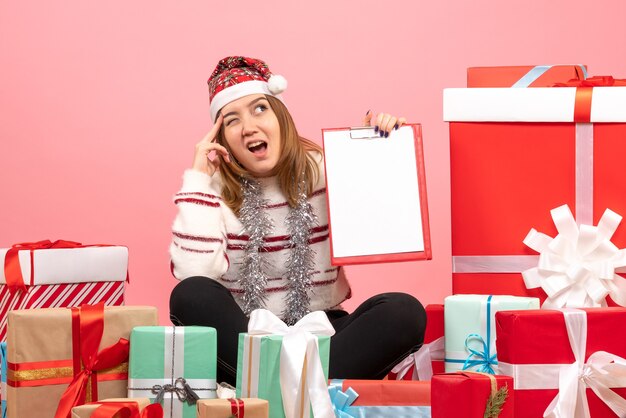 Mulher jovem sentada de frente para o Natal apresenta-se com uma nota de arquivo