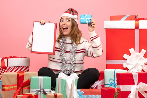 Foto grátis mulher jovem sentada de frente para o natal apresenta-se com uma nota de arquivo