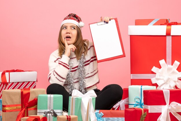 Mulher jovem sentada de frente para o Natal apresenta-se com uma nota de arquivo