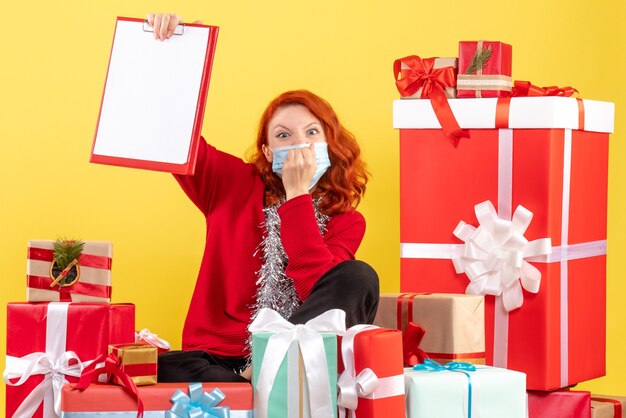 Mulher jovem sentada em frente ao Natal apresenta-se com uma nota de arquivo em amarelo