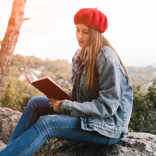 Mulher jovem, sentando, ligado, rocha, livro leitura