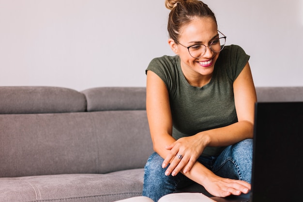 Mulher jovem, sentar sofá, usando computador portátil