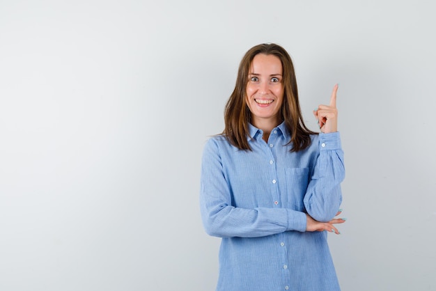 Mulher jovem sorridente aparecendo com o dedo no fundo branco