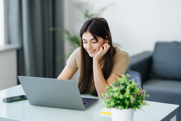 Mulher jovem sorridente com laptop no escritório em casa