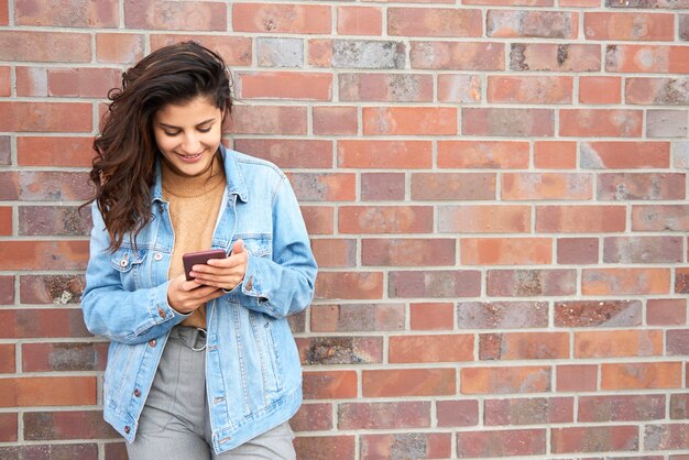 Mulher jovem sorridente com telefone inteligente na cidade