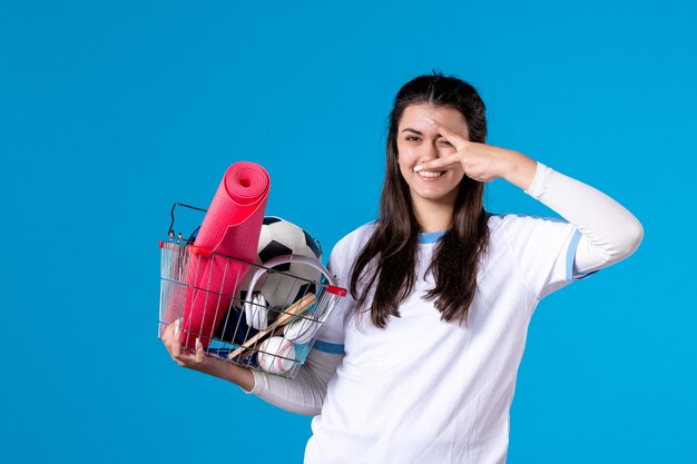 Mulher jovem sorridente com vista frontal e cesta após as compras esportivas