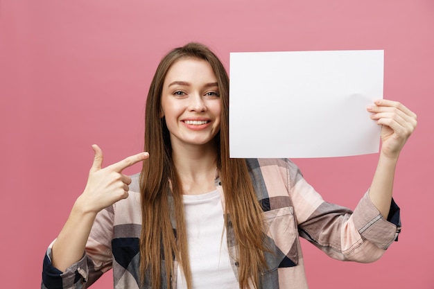 Mulher jovem sorridente em pé apontando o dedo para um quadro em branco