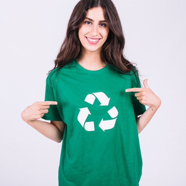 Mulher jovem sorridente, em, verde, t-shirt, mostrando, recicle ícone