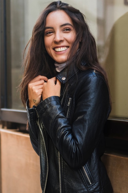 Mulher jovem sorridente, olhando para a câmera vestindo a jaqueta preta