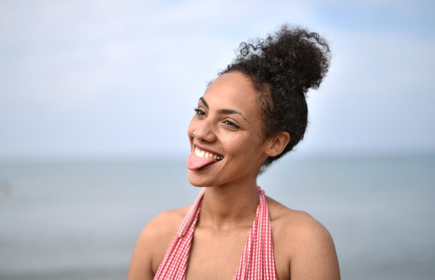 Mulher jovem sorridente usando maiô na praia - o conceito de felicidade