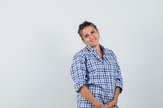 Mulher jovem sorrindo com camisa quadriculada e parecendo feliz.