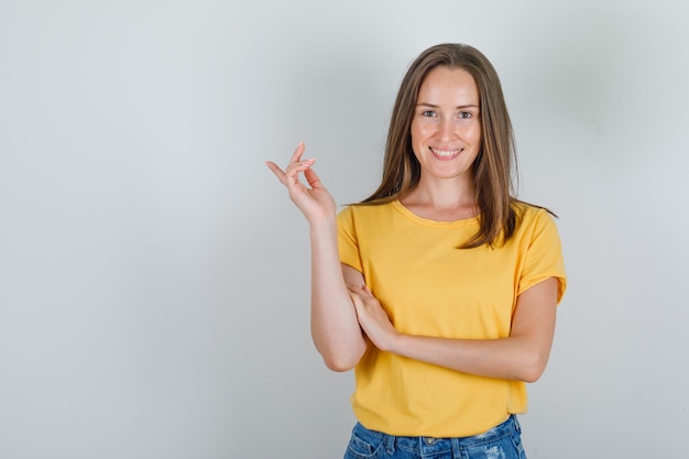 Mulher jovem sorrindo e apontando para longe em uma camiseta