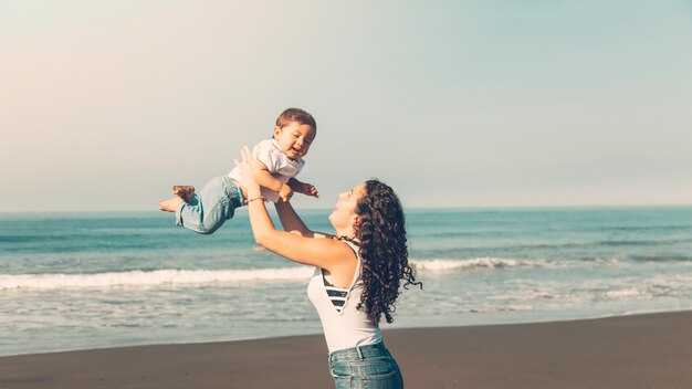 Mulher jovem, tendo divertimento, com, bebê, ligado, verão, praia