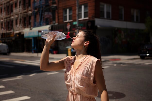 Mulher jovem tolerando a onda de calor com uma bebida gelada