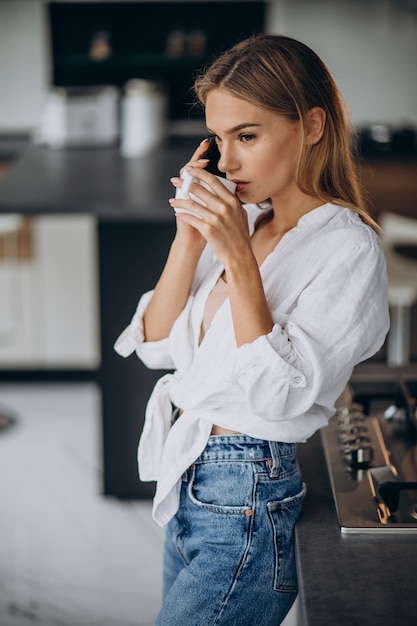 Mulher jovem tomando café na cozinha