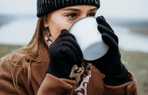 Mulher jovem tomando uma bebida quente ao ar livre