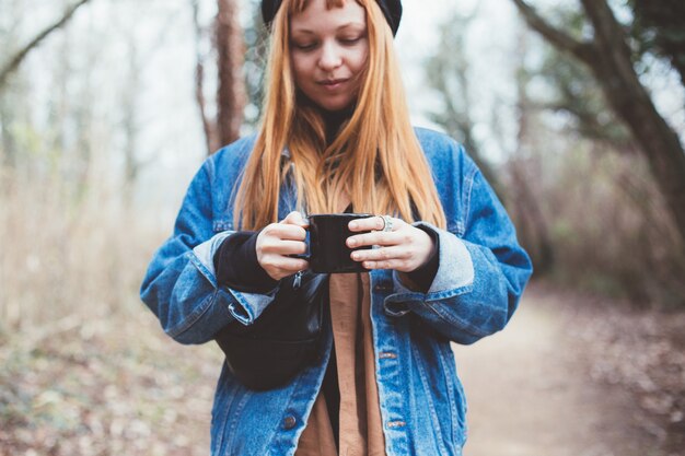 Mulher jovem tomando uma xícara de café na margem do lago